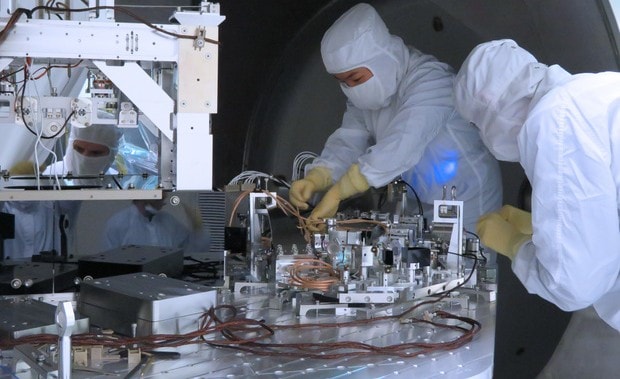 LIGO scientists in cleanroom suits assembling precision optical equipment