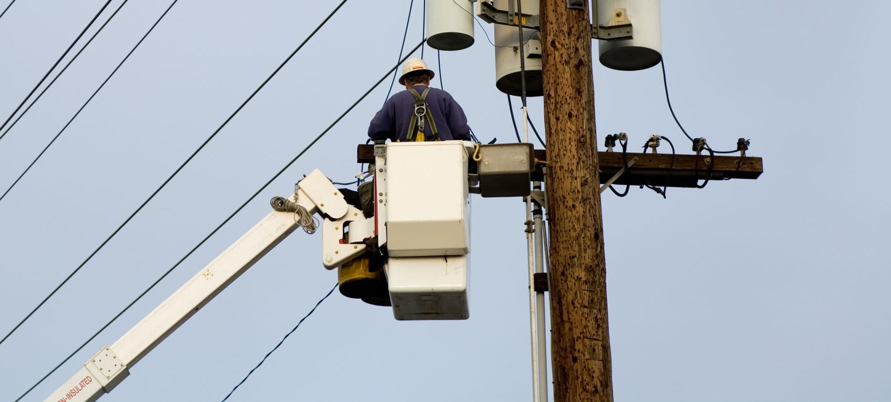 Lineman in bucket truck working on utility pole transformer